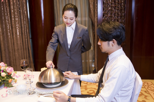 酒店服務(wù)員給顧客打開餐蓋